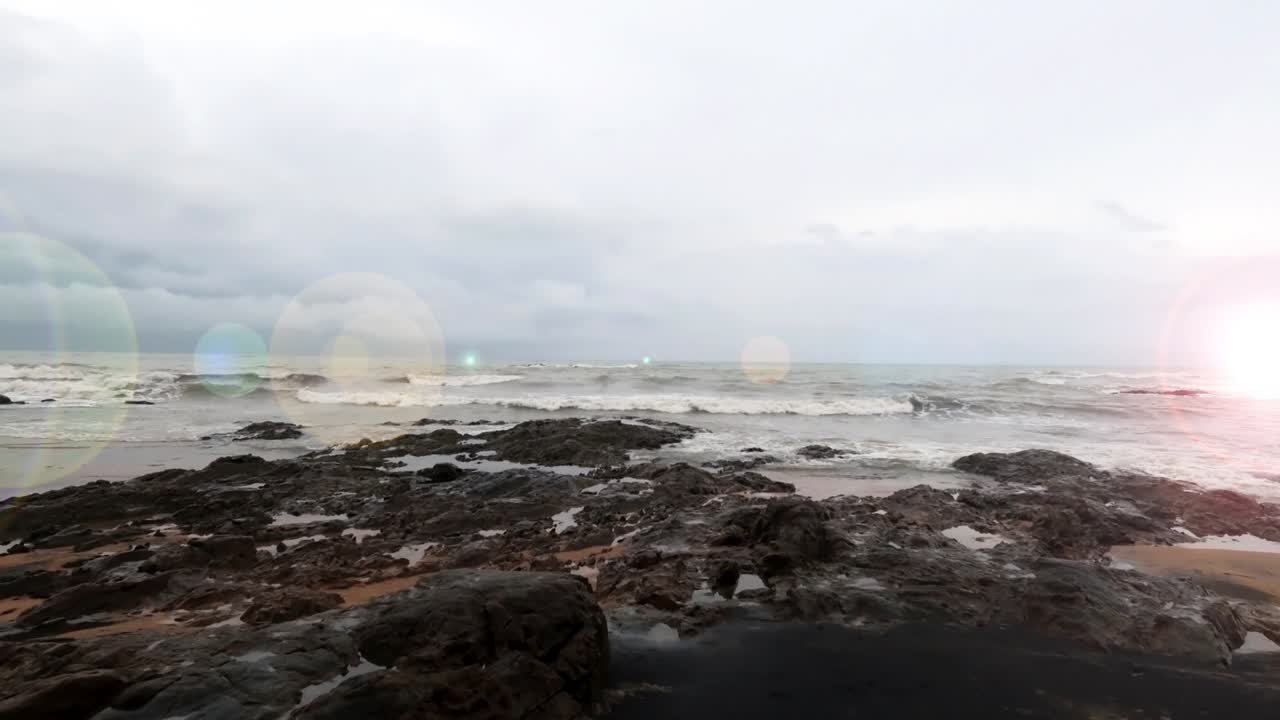 ocean wave crashing Rock stone black beach coast in bokeh sun light n sunbeam flare effect