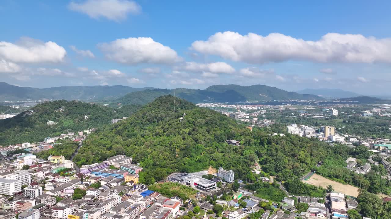 Drone fly to green hill top in Phuket city, Thailand. Beautiful sunny weather, cityscape.