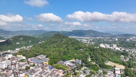 drone fly to green hill top in phuket city, thailand. beautiful sunny weather, cityscape.