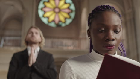 two diverse parishioners praying in christian church