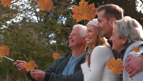 animation of autumn leaves falling over happy caucasian family in park