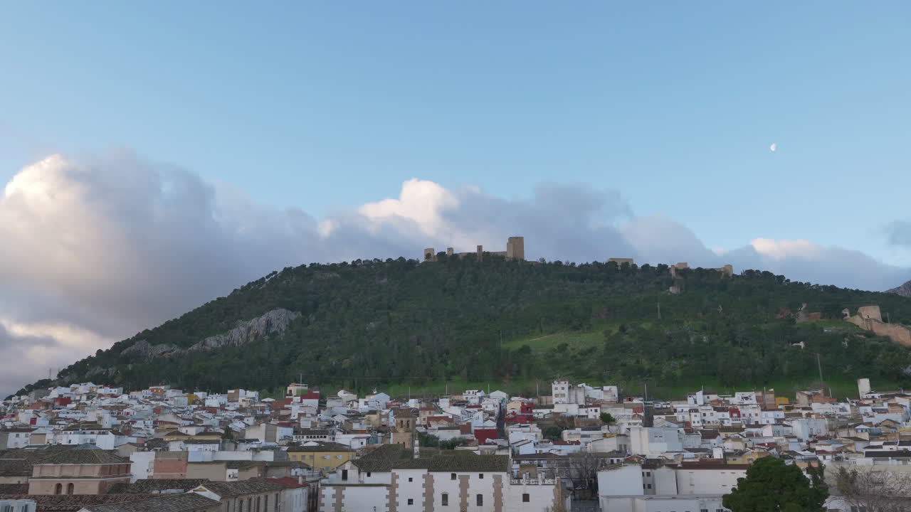 Ampia inquadratura della città di Jaén e del Castello di Santa Catalina all'alba. Time-lapse. Mostra transizioni di luce naturale, una luna crescente e nuvole.