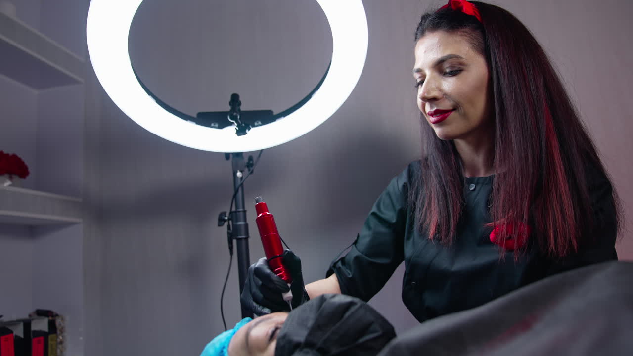 Cosmetic young specialist doing permanent make up. Pretty young woman making permanent beauty procedure.