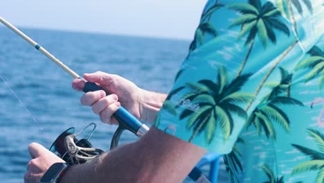 a man in a tropical shirt fishes from a boat in sunny phuket, thailand, with calm ocean surroundings