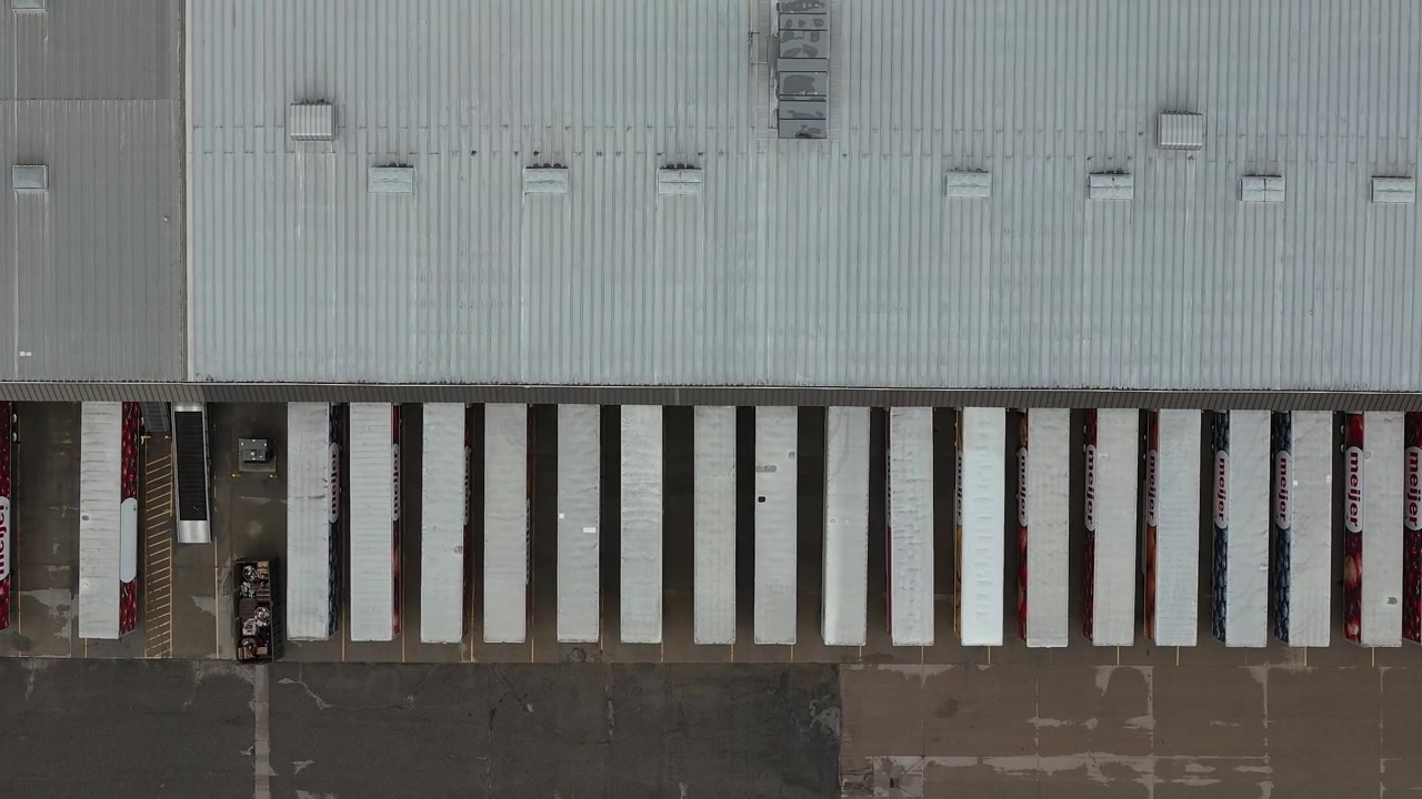 Semi trucks and trailers parked in loading stalls at a large distribution center showing freight transportation logistics and warehouse operations