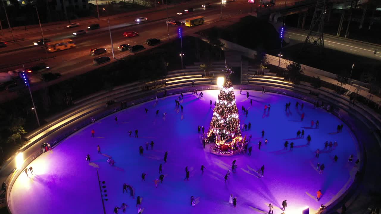 vista aérea del árbol de navidad iluminado en la pista de patinaje sobre hielo de la ciudad por la noche