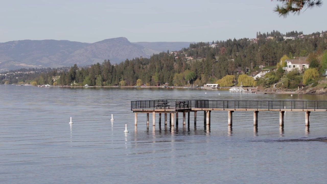 Píer de Madeira Sobre Lago Tranquilo Perto da Praia no Lago Okanagan em um Dia de Verão Calmo