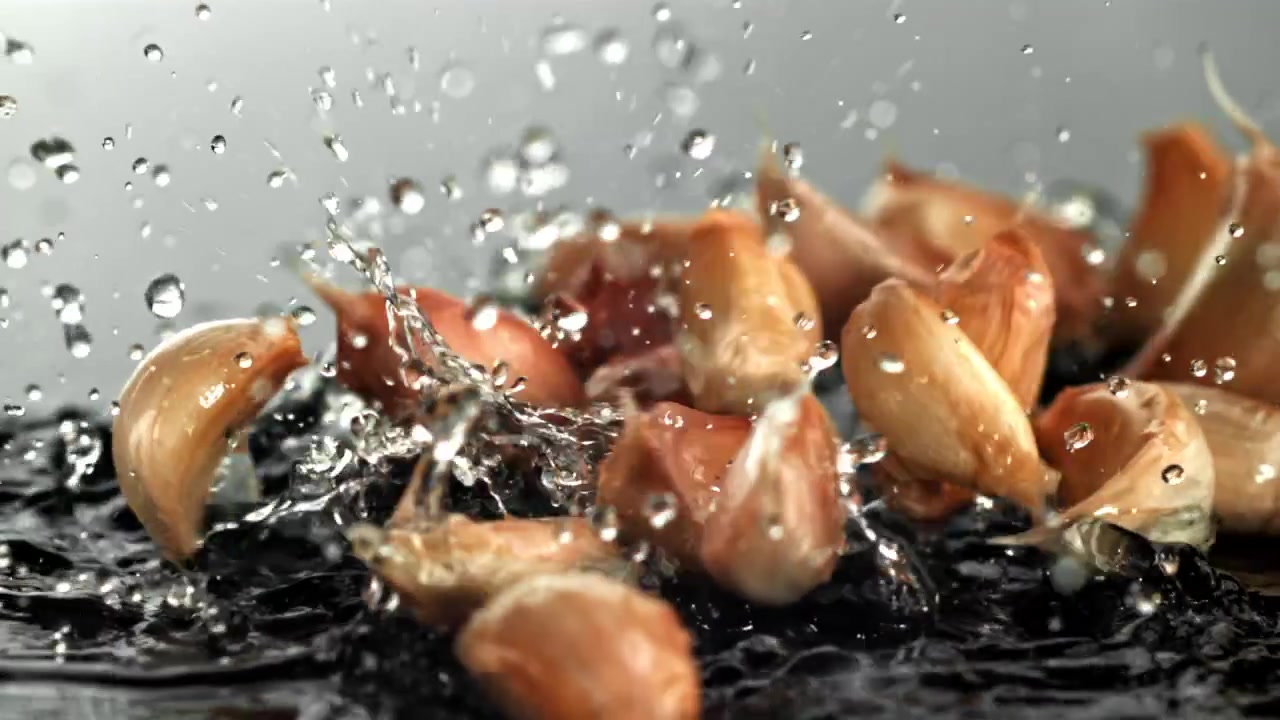 Friske hvidløgsfed falder ned i vand i slowmotion