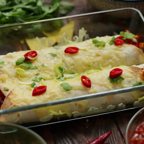 vegetable burritos served in glass heatproof dish  with salsa  guacamole  nachos and ingredients