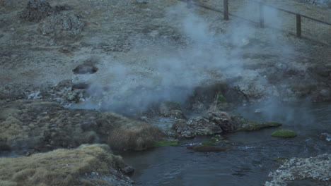 hot steam rising from hot spring at water stream, hot creek geological site, high angle