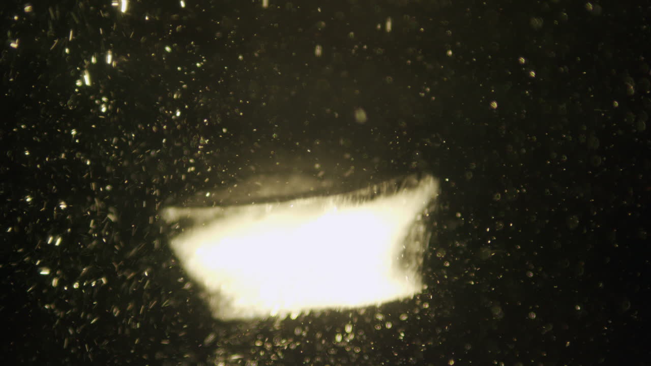 Ice cube falling in water in slow motion.