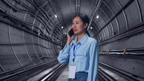 side view asian female in underground subway tunnel, she pick the phone up and started to specking to it with a slicely smile