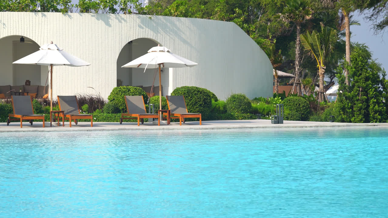 Paraply med seng pool omkring swimmingpool med hav hav baggrund - ferie og ferie koncept