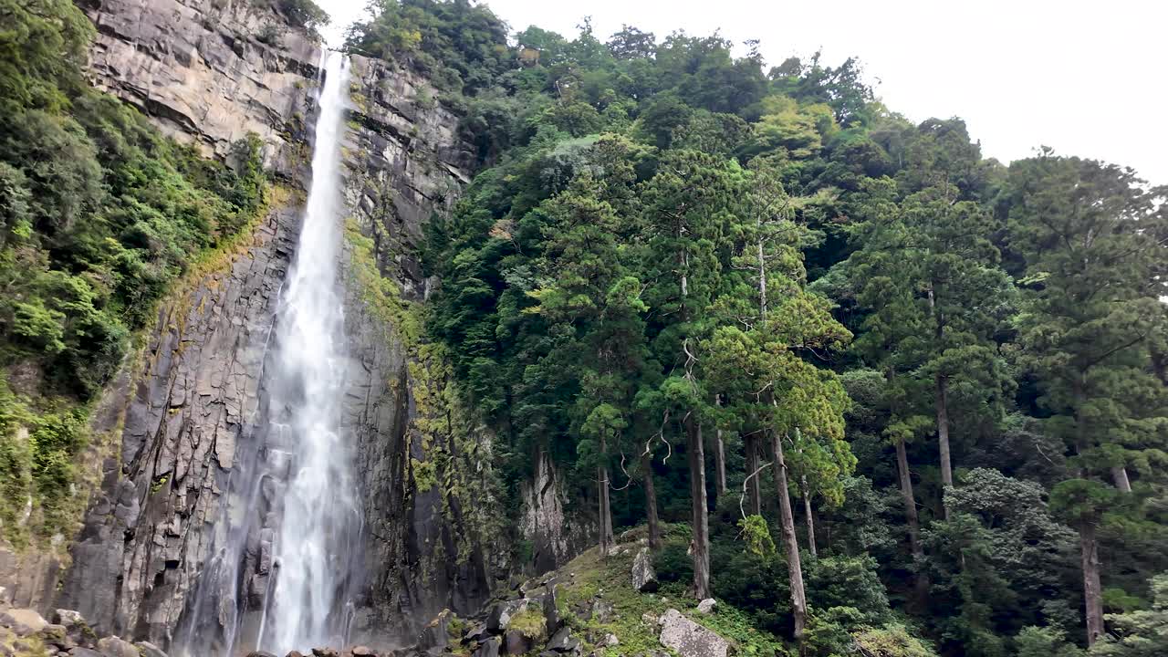 A cascading waterfall flowing through lush greenery in Nachikatsuura, Wakayama, offering a sense of tranquility and natural splendor.