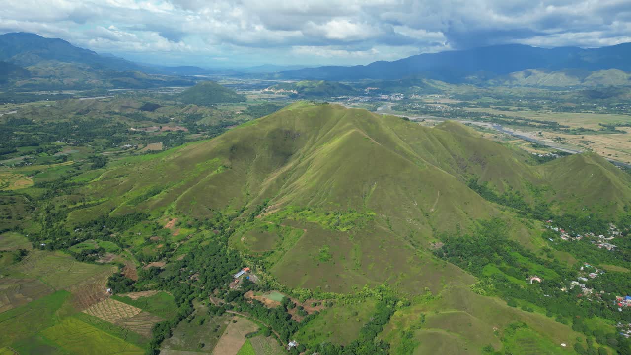 Pemandangan udara lebar dari Bagabag, perbukitan landai di bawah langit berawan yang menciptakan bayangan lembut di atas rimbunnya daerah Bagabag, Nueva Vizcaya, Filipina