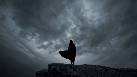 woman in a cape on a cliff during a storm