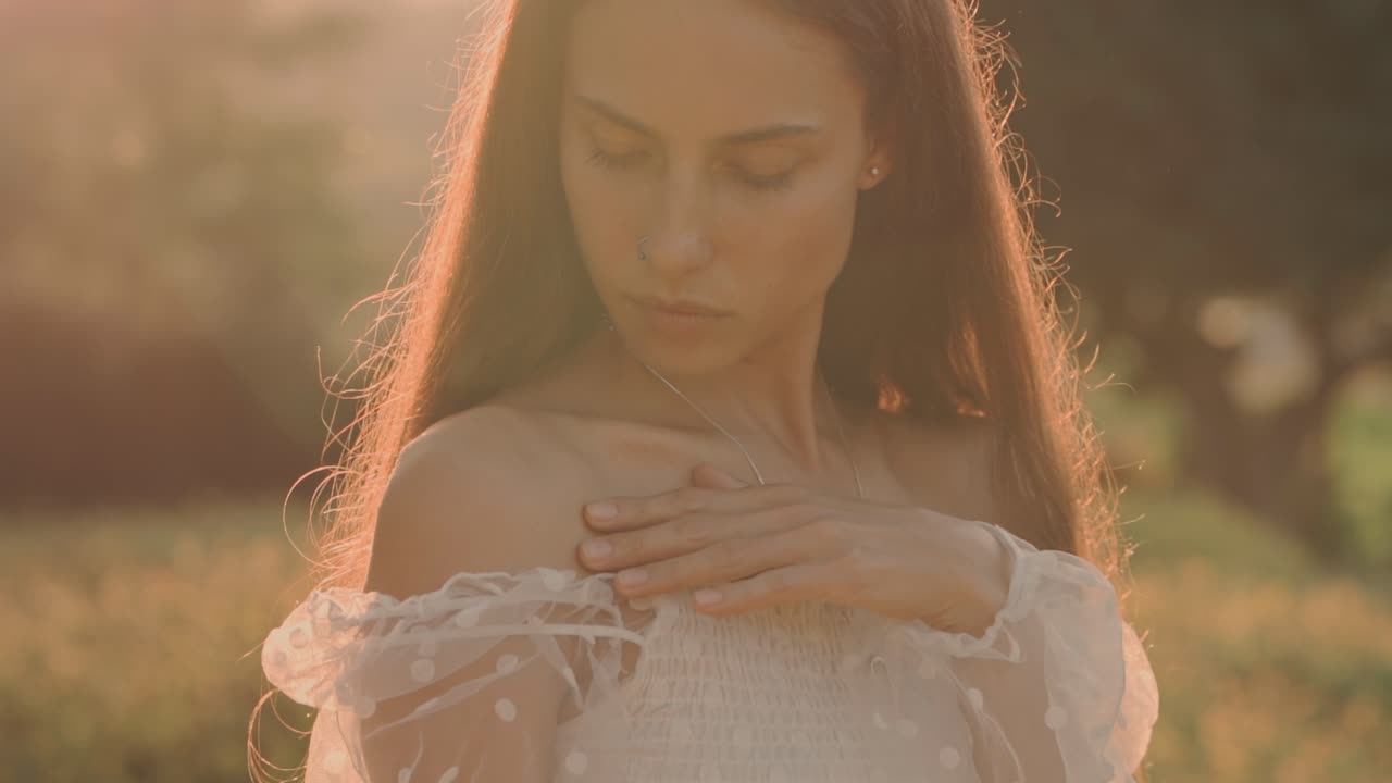 Giovane donna contemplativa in abito bianco alla luce dell'ora d'oro
