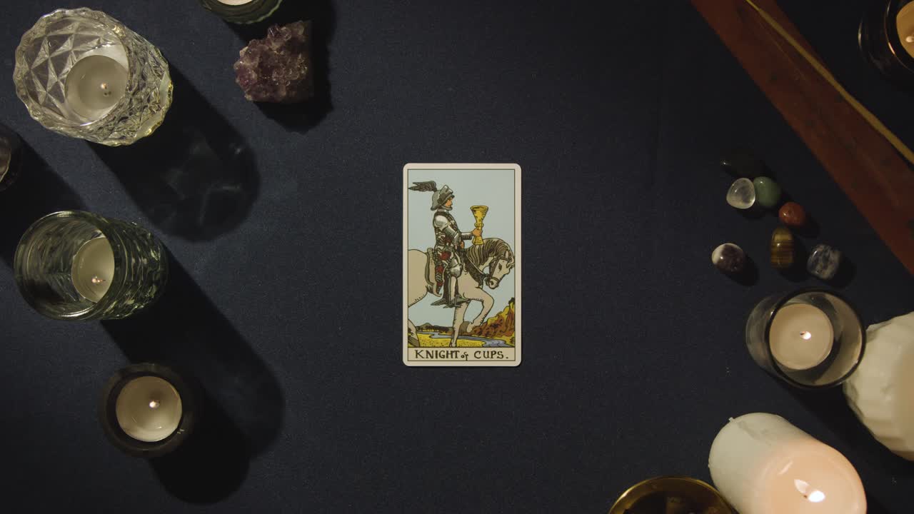 Overhead Shot Of Person Giving Tarot Card Reading Laying Down The Knight Of Cups Card On Table