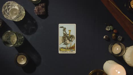 overhead shot of person giving tarot card reading laying down the knight of cups card on table