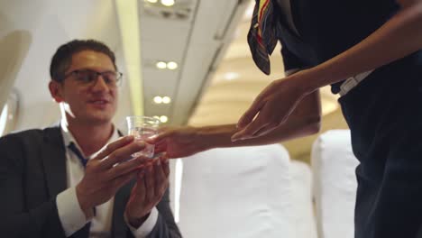 cabin crew serve water to passenger in airplane