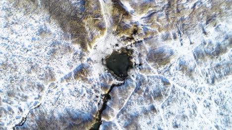 aerial-upwards-spiral-of-swimmers-inside-of-saratoga-hot-springs-in-provo-utah-enjoying-the-steam-and-daylight-sunlight-with-the-ground-covered-in-snow