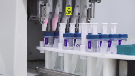 close-up in the medical laboratory, the robot pierces a jar of liquid with a needle and pours it into a tube for further analysis by the doctor