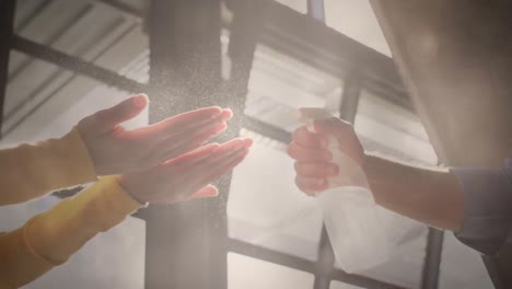 video of light over diverse colleagues disinfecting hands at work