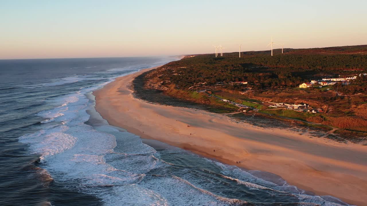 playa praia do norte en nazare portugal con olas de cuerda y turbinas eólicas en la distancia, tiro aéreo a la izquierda