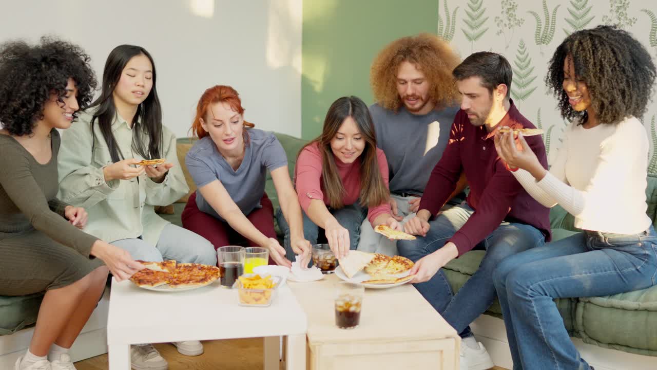 Multiracial group of happy friends eating pizza at home
