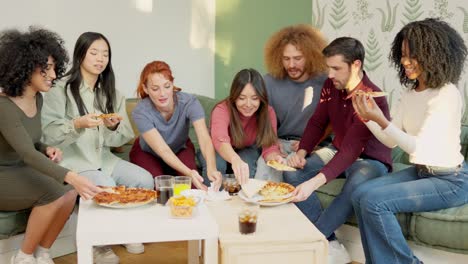 multiracial group of happy friends eating pizza at home