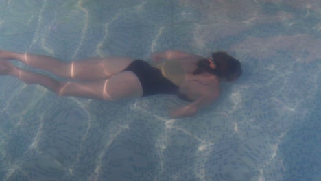 una hermosa joven nadando bajo el agua en una piscina