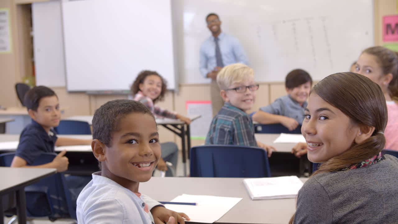 Back view of young students in class turning round to camera