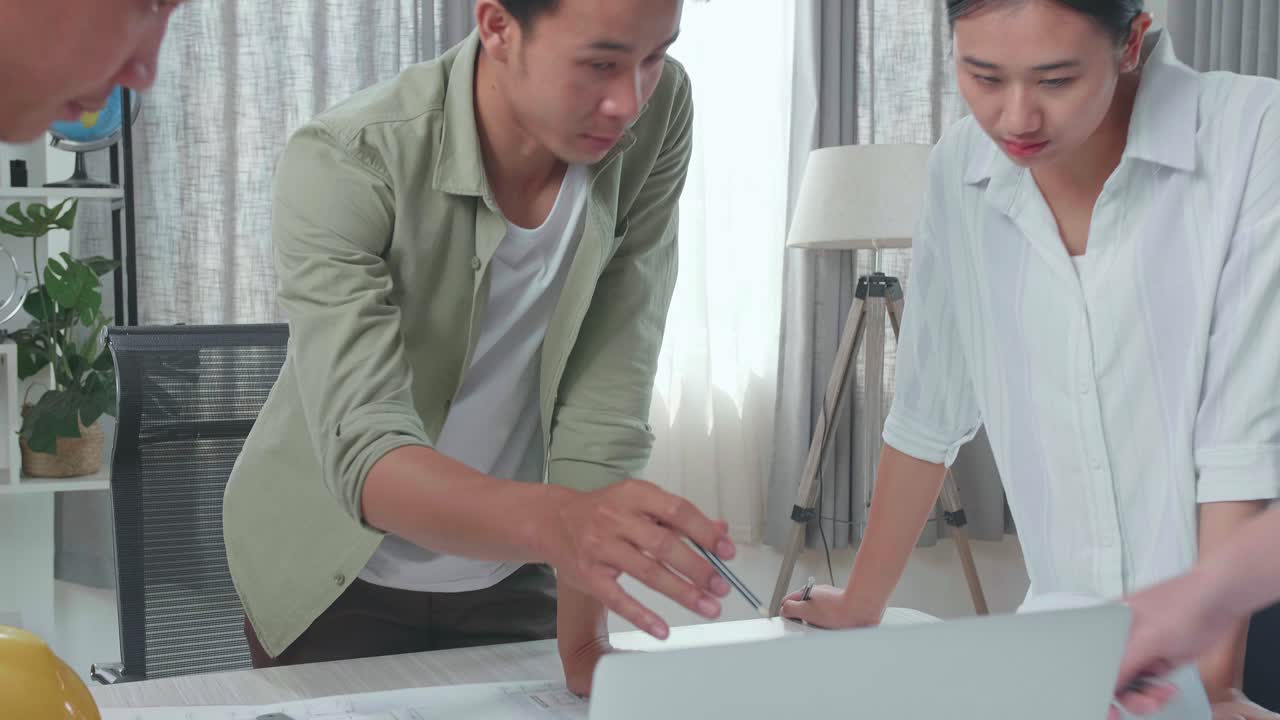 Group Of Asian Engineers Discuss About Work On Laptop At The Office