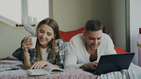 pareja relajándose en la cama con una computadora portátil