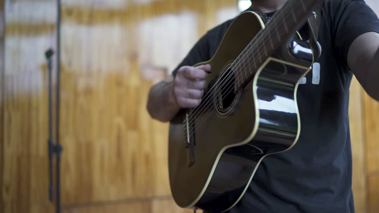 Close-up view of musician playing acoustic guitar indoors at celebrating