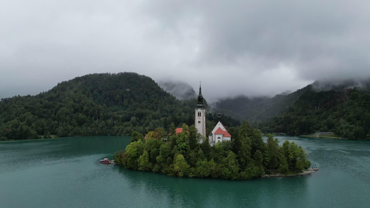 Bleder See, Slowenien: Drohnen-Luftaufnahme mit tiefen Wolken, die bewaldete Hügel im Hintergrund bedecken