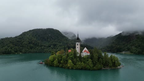 lake bled slovenia drone aerial view low clouds covering wooded hills in background