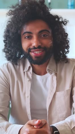 smiling man with curly hair in a cozy indoor setting