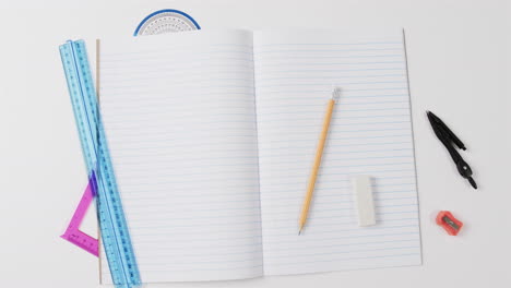 overhead view of open notebook with school stationery on grey background, in slow motion