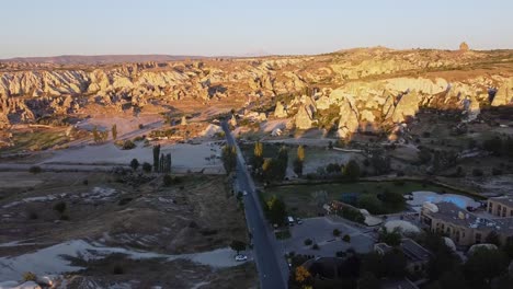 Vista-Aérea-De-La-Carretera-De-Acceso-Pavimentada-Con-Coches-A-Formaciones-Rocosas-De-La-Ciudad-De-Capadocia-En-Turquía.