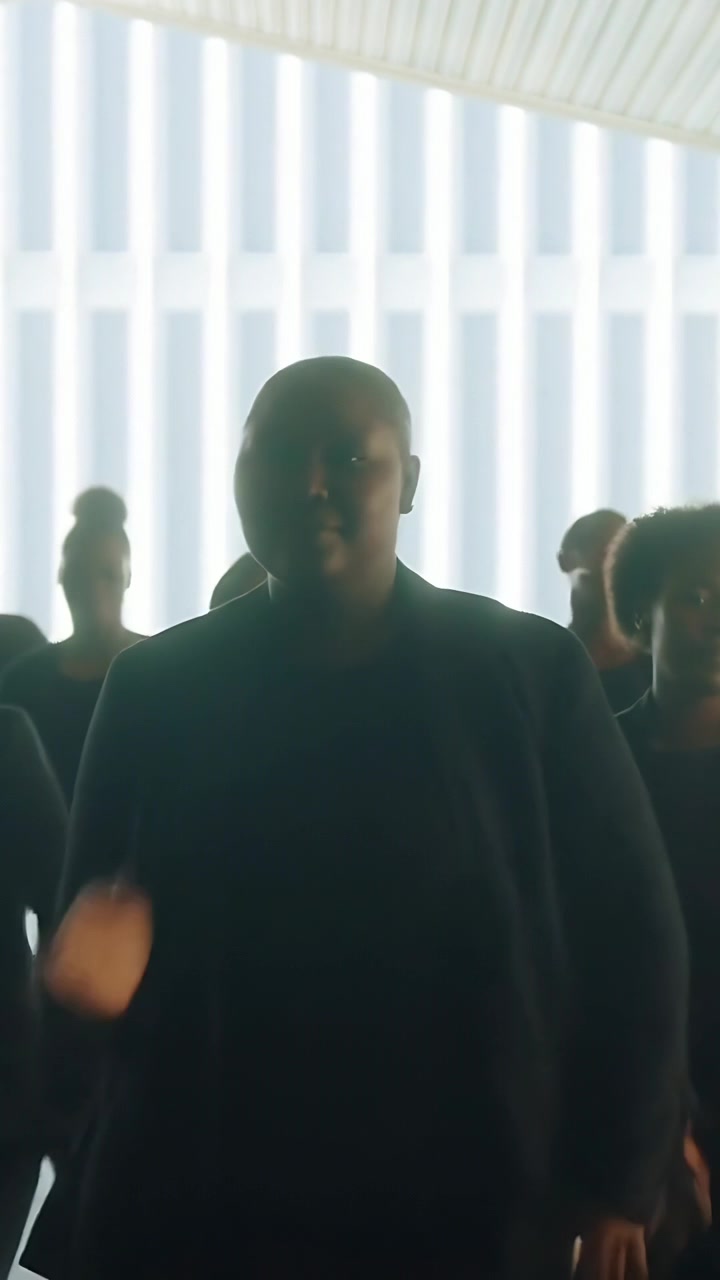 Video verticale: Artista principale che avanza eseguendo una routine in uno studio con pannelli illuminati e blazer scuri