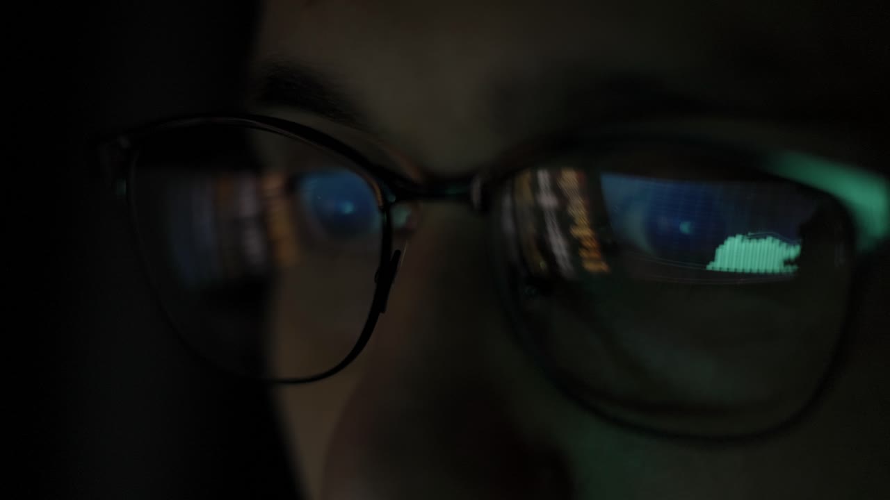 hombre de negocios trabajando por la noche mirando el monitor, reflejos en las gafas.