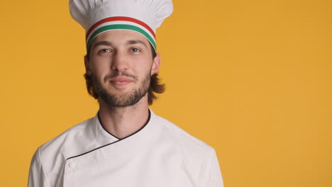 chef caucásico frente a la cámara sobre un fondo amarillo.