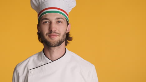 caucasian chef in front of camera on yellow background.