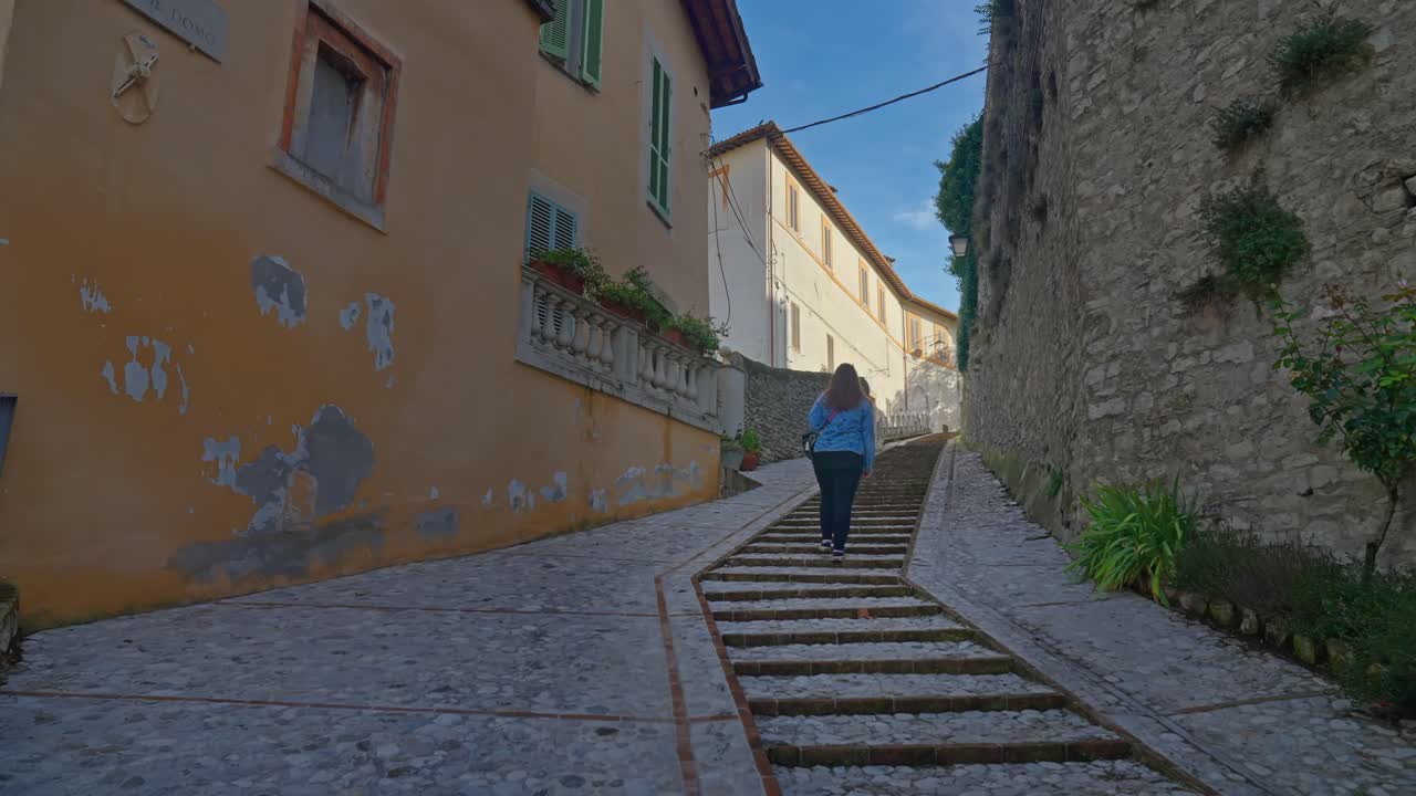Una donna cammina su un vicolo lastricato nel centro storico di Spoleto, Umbria, Italia.
