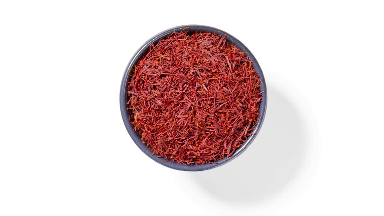Safran threads spice in round bowl on white background, seamless loop
