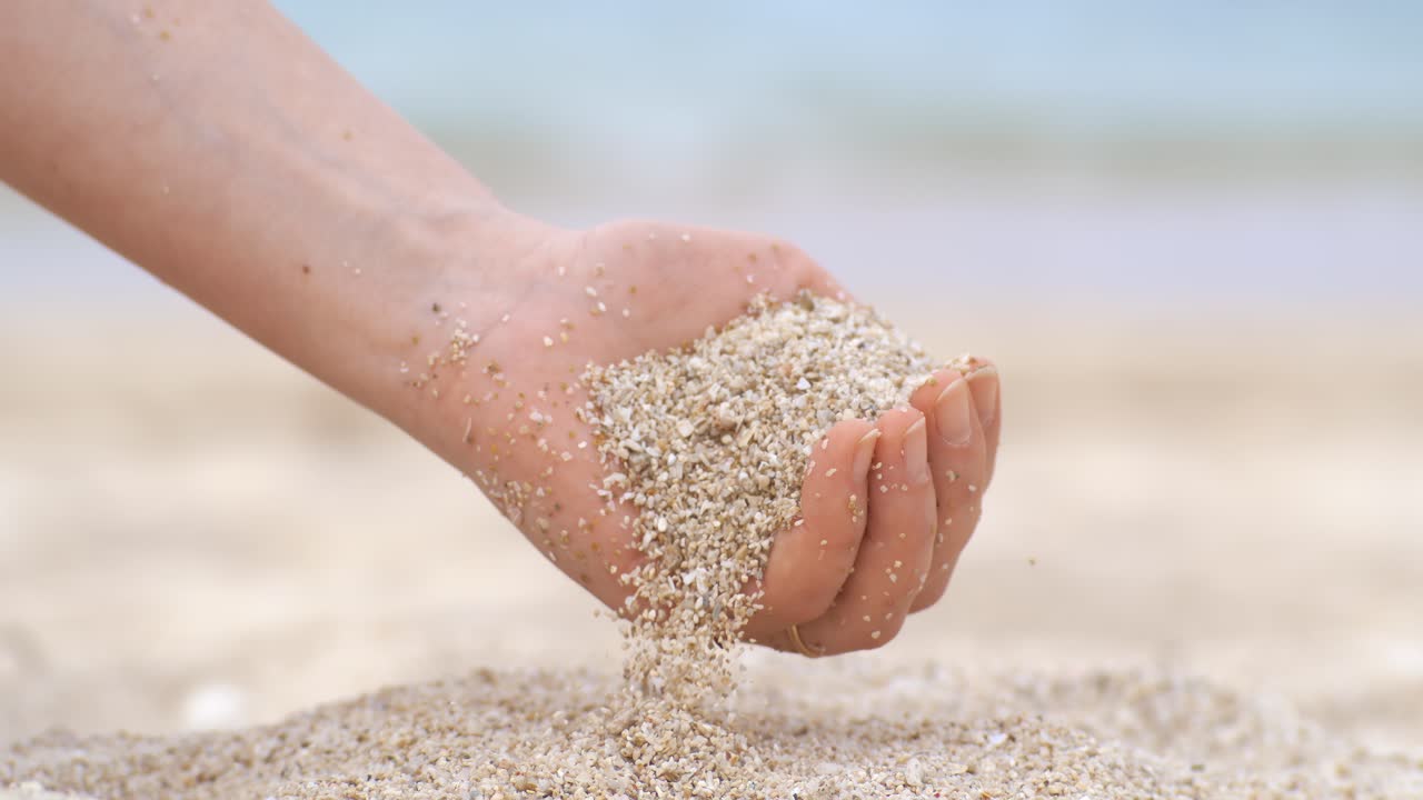 Sand falling from hand in slow motion on a beach. Vacation and travel concept. Shot on super slow motion camera 1000 fps