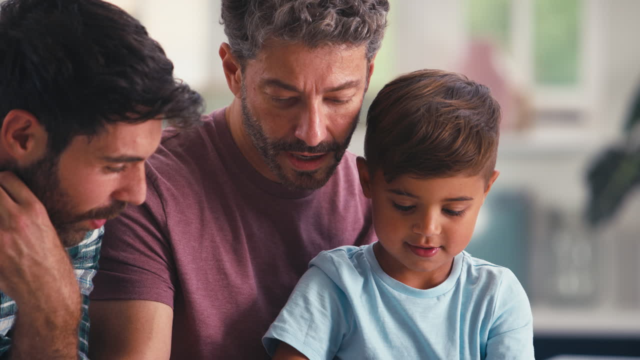 primer plano de una familia del mismo sexo con dos padres e hijo haciendo rompecabezas en la cocina en casa