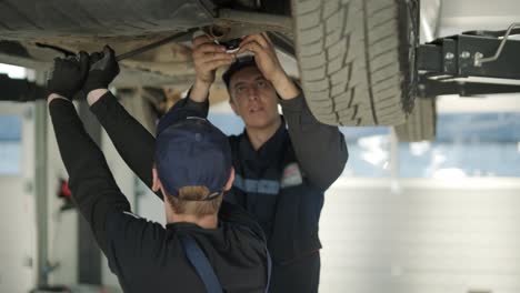 team of mechanics repairing car suspension