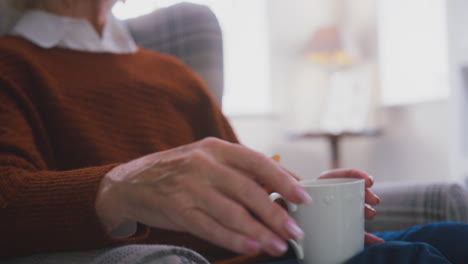 Ältere-Frau-Mit-Heißgetränk-Hält-Sich-Zu-Hause-In-Der-Lebenshaltungskostenkrise-Am-Tragbaren-Heizkörper-Warm